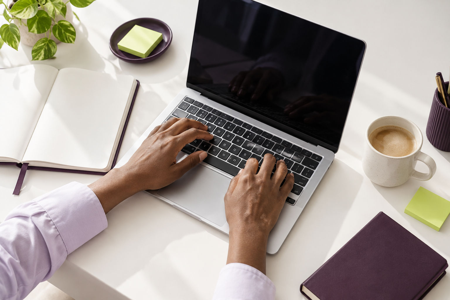 Des mains à un bureau lumineux avec un ordinateur portable, un carnet et des notes vert citron